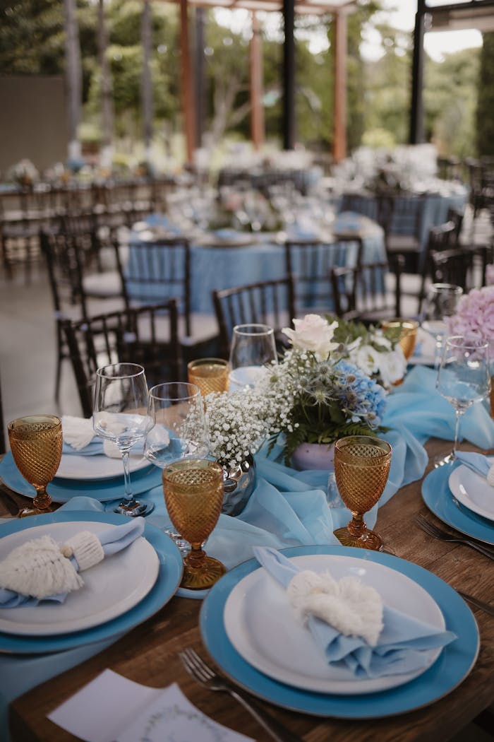 Mastering the First Impression: Your intriguing post title goes here Beautifully decorated outdoor wedding reception table with blue theme and floral centerpiece.